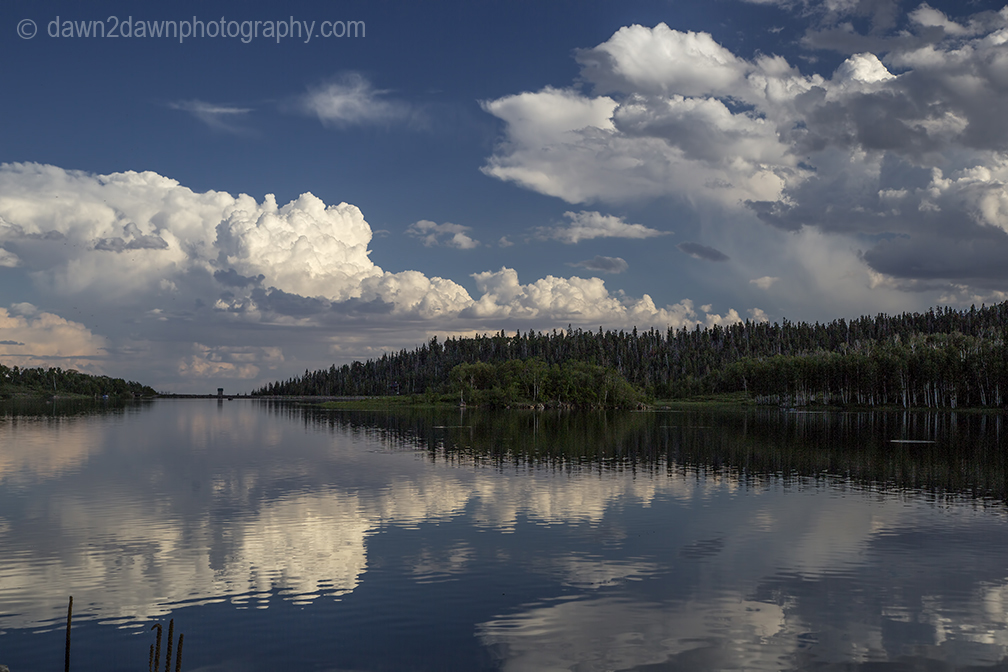 Passing clouds are reflected in the still waters of Kolob Reservoir near Zion National Park, Utah