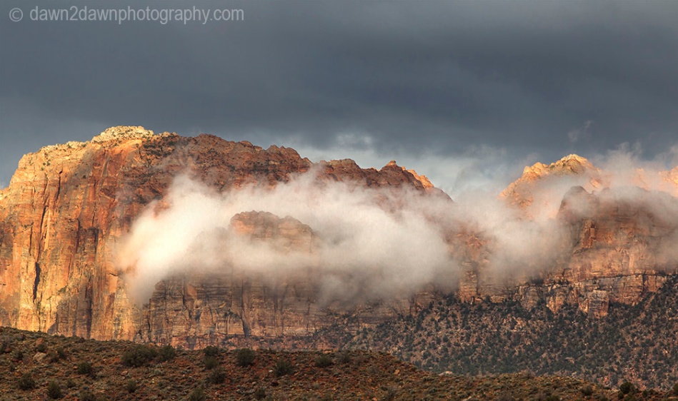 A passing storm produces clouds around The Watchman at Zion National Park, Utah
