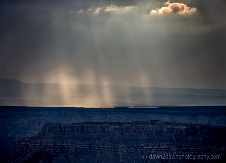 Storm clouds pass over the Grand Canyon and produce sunbeams near Timp Point, Kaibab National Forest, Arizona