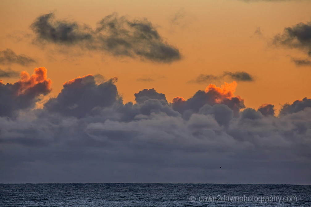 The light from the setting sun casts a soft light on clouds over the Pacific Ocean at California's central coast.